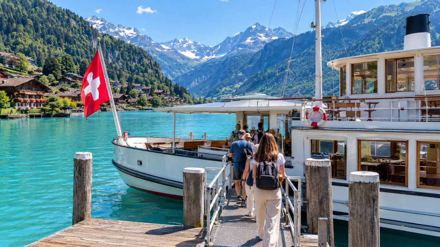 Passengers seen from behind walking up a gangway onto a white lake ship